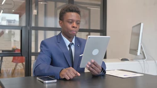 Young African Woman Doing Video Chat on Tablet at Workplace