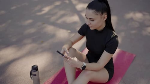 Athletic Woman Using Phone on Yoga Mat