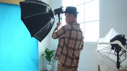 Jeune photographe installant l'éclairage pour une séance photo en studio