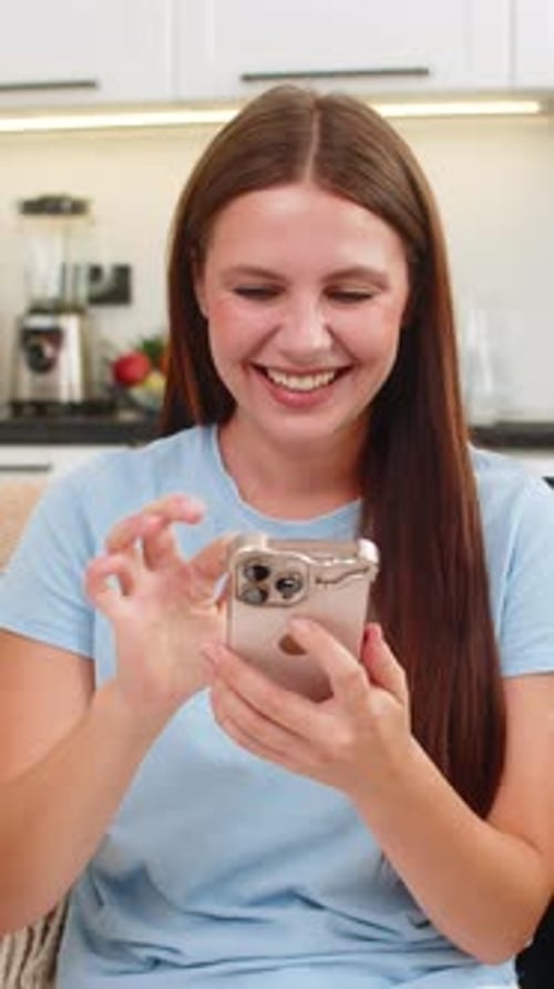 Happy Woman Uses Phone in Kitchen at Home