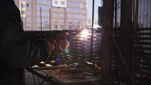 Welder Works at a Construction Site Sparks and Smoke Fly