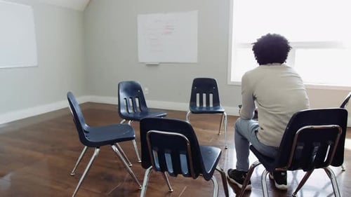 Young man seated in community center awaits start of support group meeting
