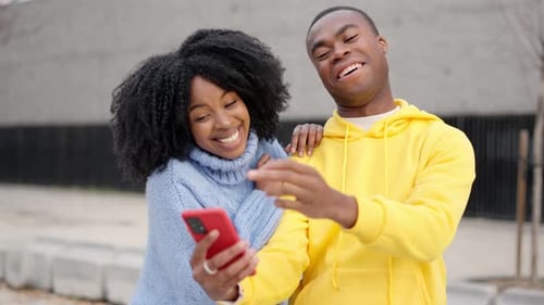 African Couple Having Fun Using Mobile in the Street