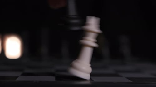 Vue rapprochée d'un échiquier pendant qu'un joueur renverse le roi et remporte la partie.