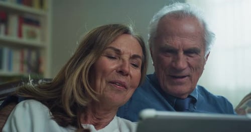 Cinematic shot of happy modern mature senior couple is using a tablet for family entertainment whi