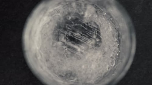 Ice cube dropping in clear water glass close-up shot