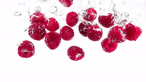 Ripe and Delicious Raspberries are Falling and Plunging Into Water Filmed in Slow Motion