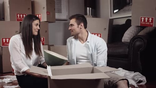 Happy Couple Unpacking Moving Boxes in New Home