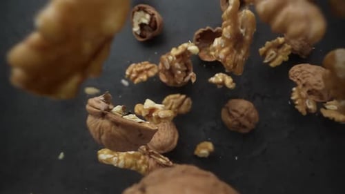 Walnuts Falling on Dark Textured Surface