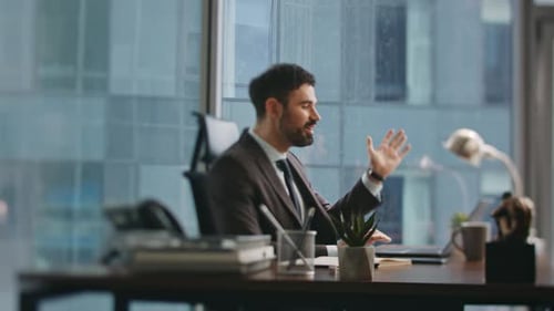 Businessman Having Virtual Meeting with Team Looking Laptop at Office Desk