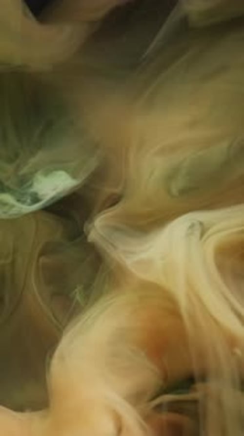 Swirling golden and green inks floating