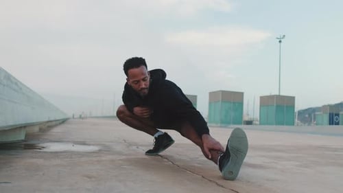 Young athlete doing warm-up, leg stretching before training on the embankment