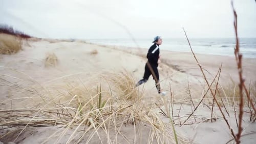young man with black sportswear running in the beach
