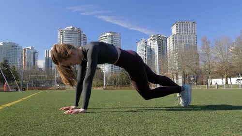 Athletic young woman doing mountain climber abdominal workout exercise in park