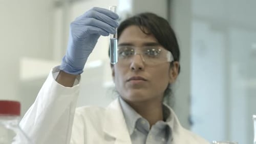 Woman Scientist Examining Test Tube with Blue Liquid