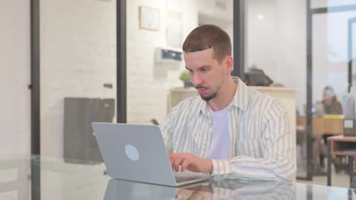 Creative Young Man Working on Laptop in Office