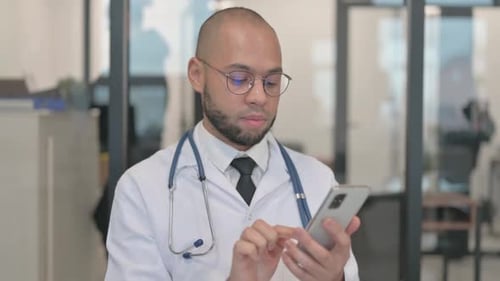Doctor Typing on Cell Phone in Office Setting