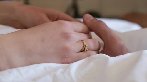 lovers holding hands in bed