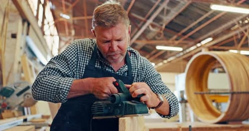 Man Smoothing Wood with Power Tool in Workshop