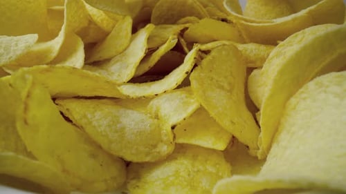 Makrovideo von Kartoffelchips, die in eine Schüssel fallen. Aufgenommen mit der ROTEN Heliumkamera in 8K.