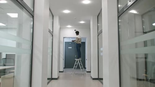 Young Adult Working on Laptop in Office Hallway