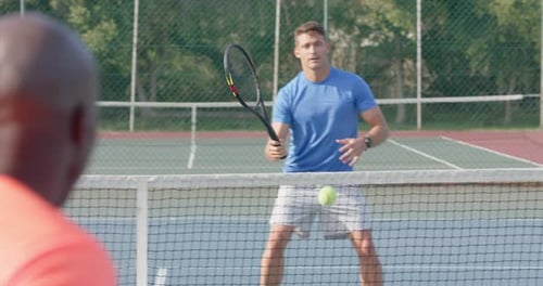 Diverse male tennis players playing on outdoor tennis court in slow motion