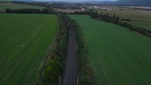 Aerial view of a train viaduct with a passing train and the surrounding countryside and city in the