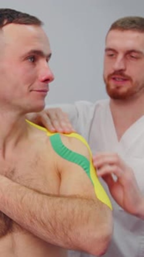 Medical Professional Applying Therapeutic Tape to Man's Shoulder