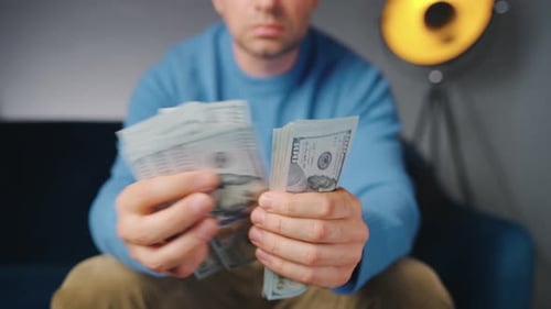 Man Counting Stack of United States Currency Indoors