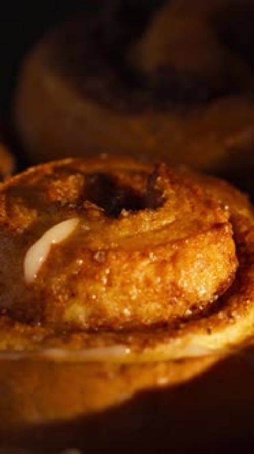 Icing Being Drizzled on Golden Cinnamon Rolls