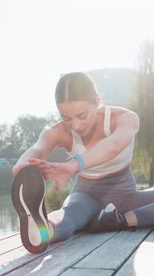 Caucasian Young Woman Stretching Leg in the City Park for Fitness Health and Wellness Before a Run
