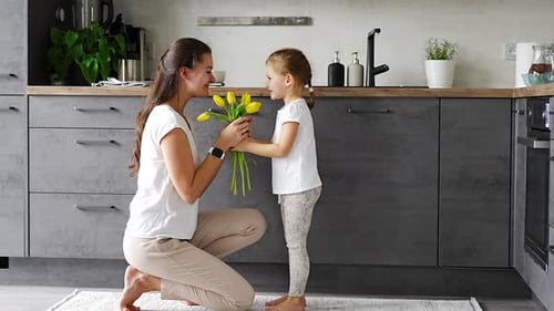 Little Girl Gives Mother Flowers in Kitchen