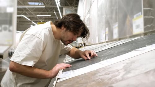 Man Inspects Tile Texture By Touch in Hardware Store