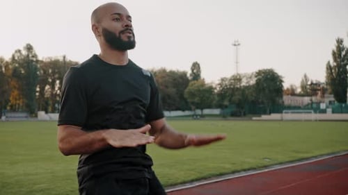 Sportsman Runs in Place with High Raising of Knees on Track