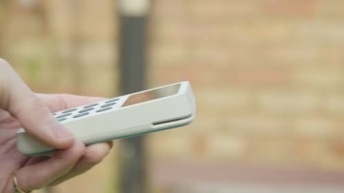 Female using contactless payment in outside bar on her phone