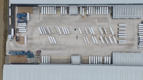 Cinematic drone top down aerial overhead footage of huge warehouse logistics park with trailers,