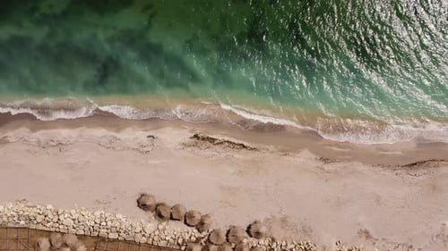 Aerial View of Waves and Water Crashing On To Sandy Beach