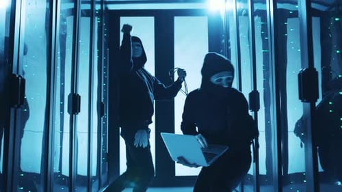 Figures in Hoodies in a Dimly Lit Server Room