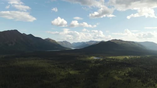 Aerial footage of beautiful forest wilderness with mountains rivers and lakes. Blue sky and clouds o