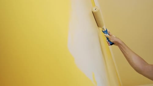 Mann malt Wand im Zimmer. Nahaufnahme eines Mannes in einer neuen Wohnung, der das Zimmer renoviert und die Wand bemalt