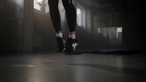 Nahaufnahme der Beine einer athletischen Gewichtheberin, die im Smokey Gym mit Springseil springt