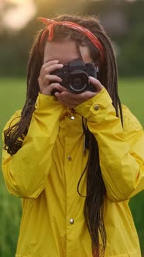 Smiling Woman Takes Photos Outdoors in Yellow Raincoat