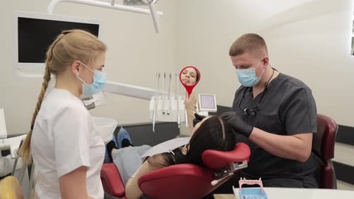 Dentist Examines Patient with Assistant in Office