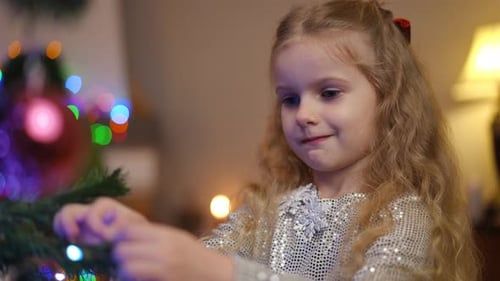 Girl Decorating Christmas Tree with Colorful Lights