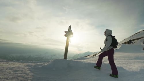 Hiker woman looking at a sign on a snowy mountain