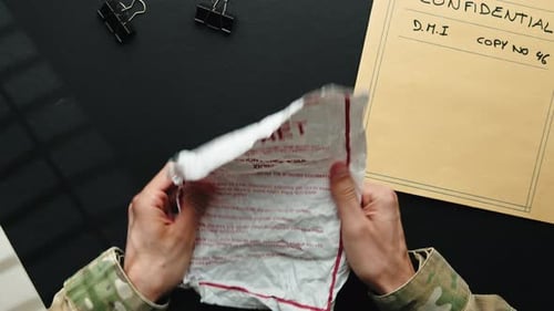 Soldier Uncrumples Secret Document on Desk