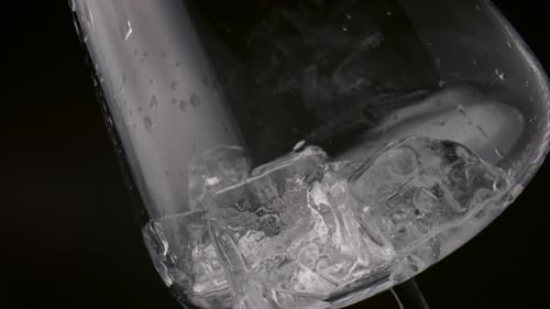 Crystal ice cubes lying inside empty wineglass close up on black background