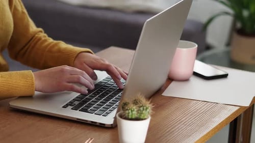 Hands Typing on Laptop at Wooden Desk