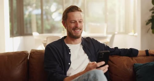 Funny, cellphone and man on sofa in home with networking, contact or social media scrolling