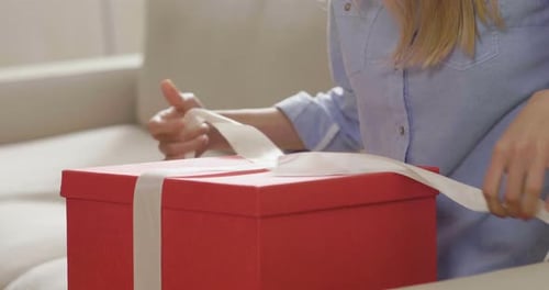 Close up of an young woman is opening a gift box arrived at home ordered by using online shopping.